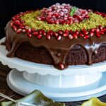 圣诞节巧克力蛋糕用ganache，石榴种子和地面开心果在蛋糕立场。