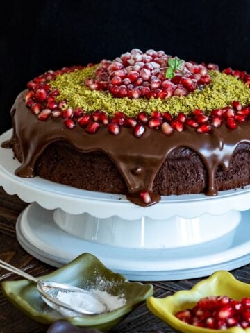 圣诞巧克力蛋糕配甘纳许，石榴籽和磨碎的开心果放在蛋糕架上。