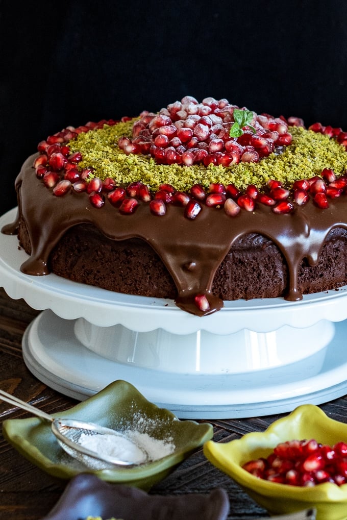圣诞节巧克力蛋糕用ganache，石榴种子和地面开心果在蛋糕立场。