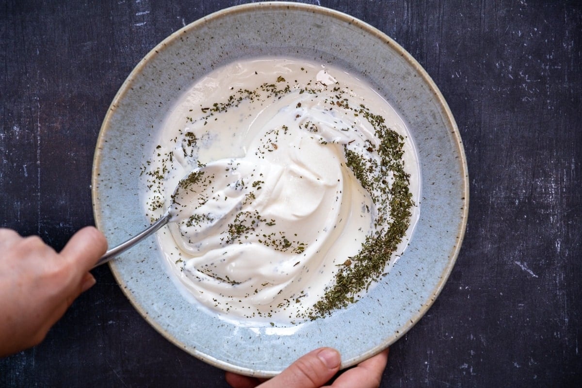 用勺子将酸奶、干薄荷和盐混合在一个蓝色的大碗里。