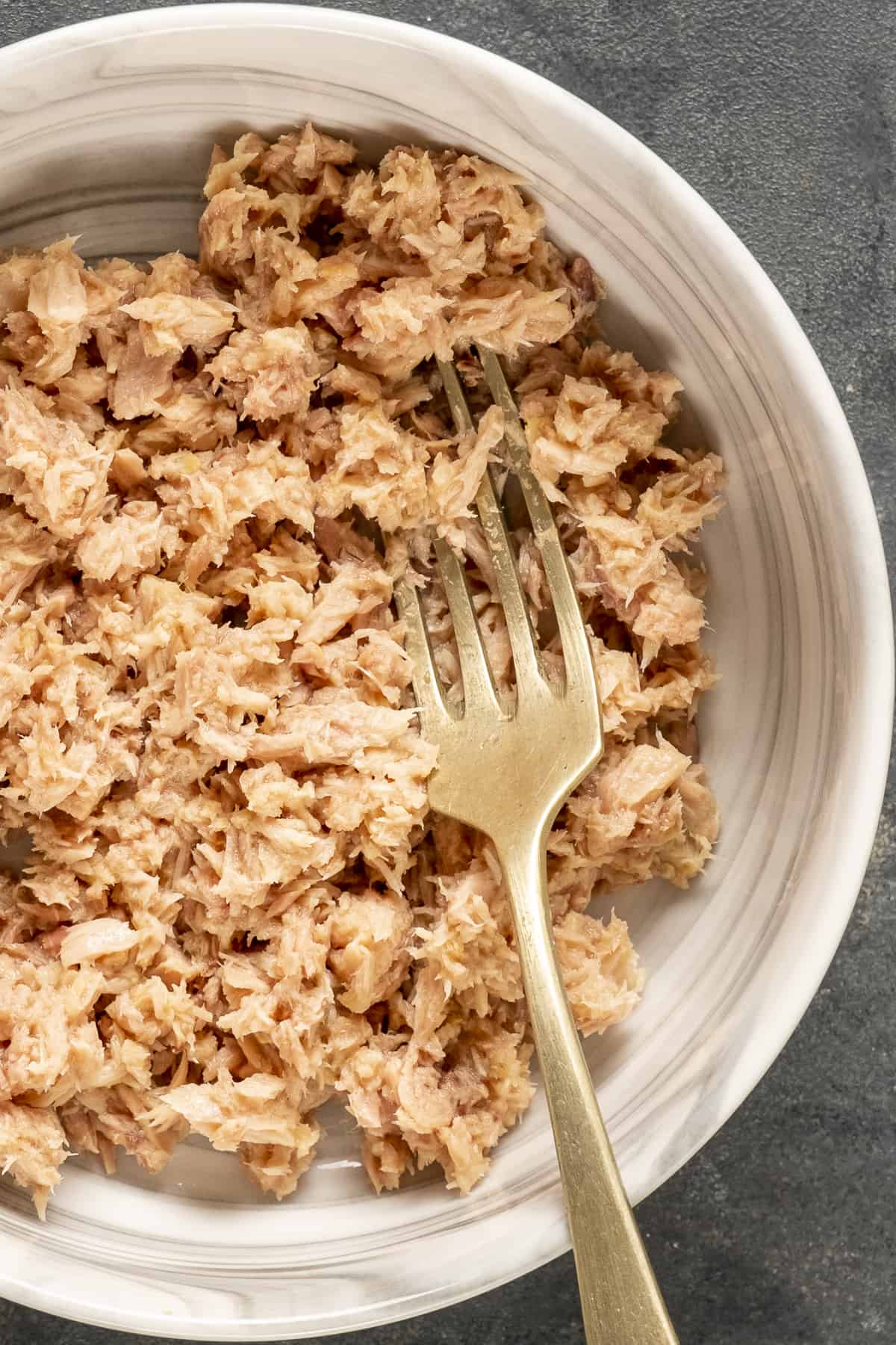 一片金枪鱼肉放在白色的碗里，里面放着一把叉子。