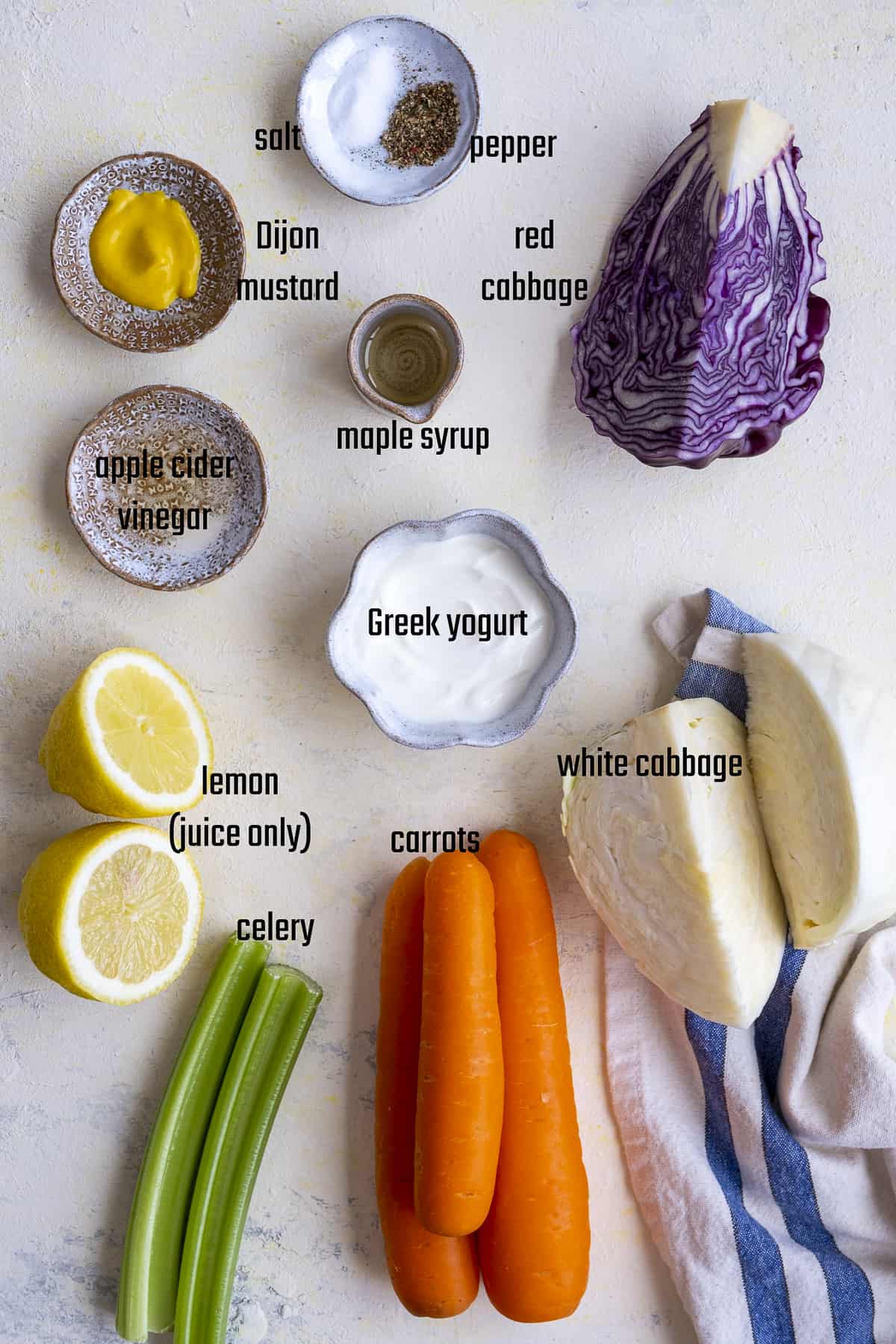 红卷心菜,白菜,胡萝卜,柠檬、芹菜根肋骨,希腊酸奶,第戎芥末、醋、枫糖,盐和胡椒在光背景。