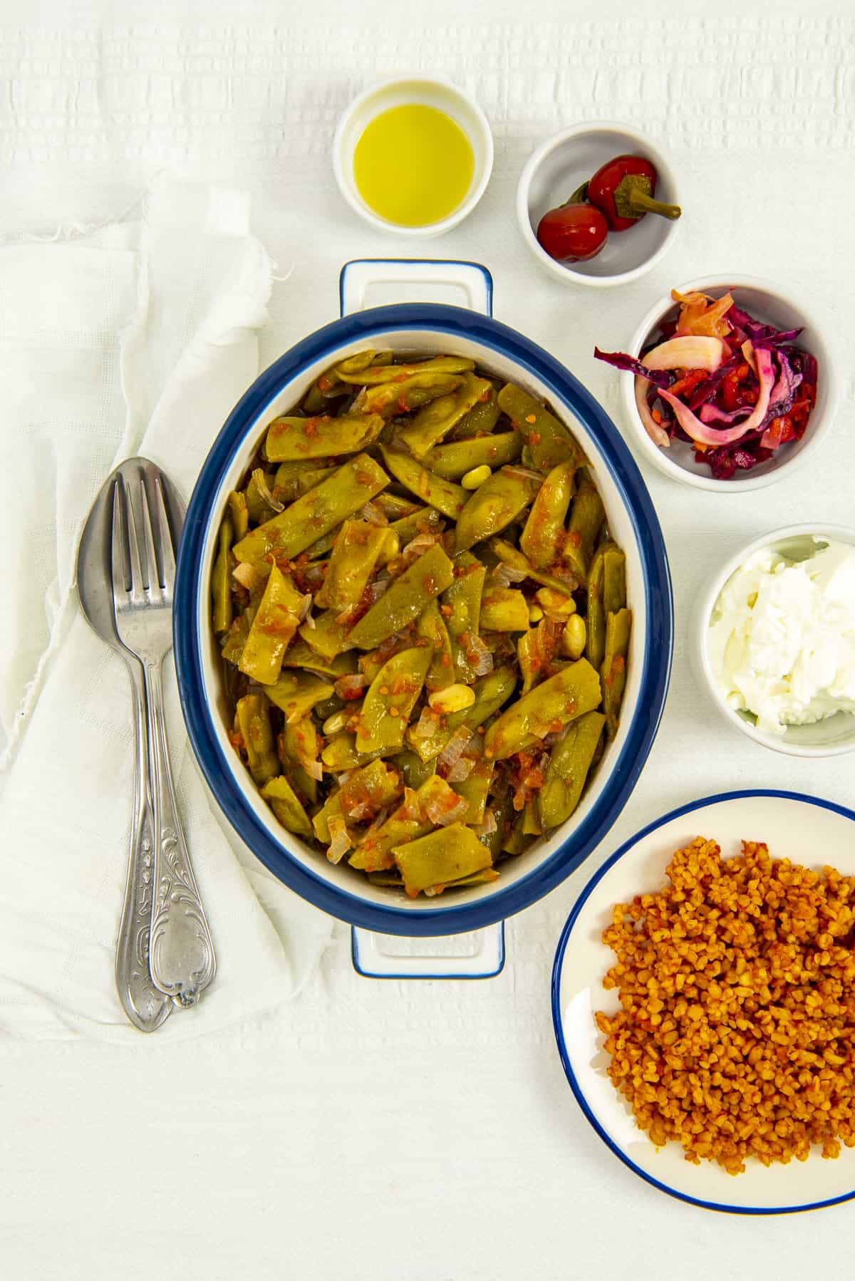 土耳其青豆盛在白色的椭圆形盘子里，面包抓饭、咸菜和酸奶放在旁边。