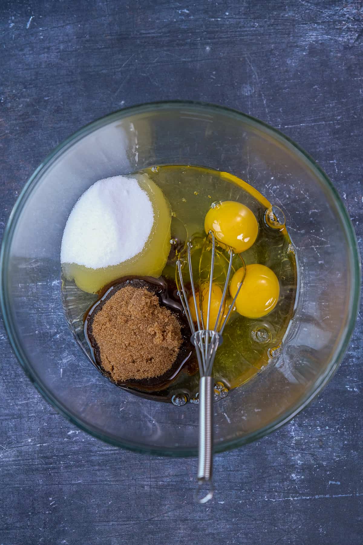 鸡蛋，黑糖和砂糖放入一个玻璃搅拌碗中，里面有一个搅拌器。