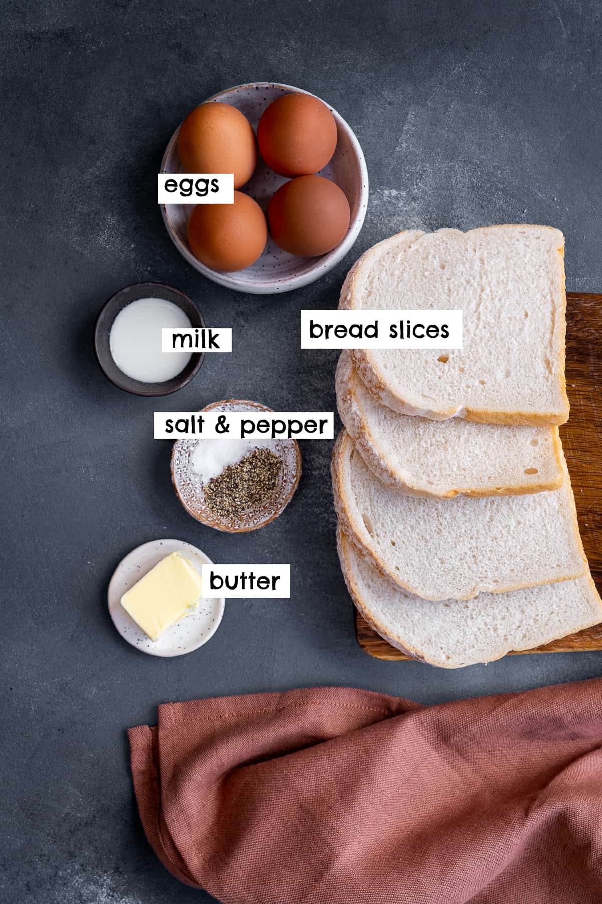 面包片、鸡蛋、牛奶、黄油、盐和胡椒，背景是灰色的。