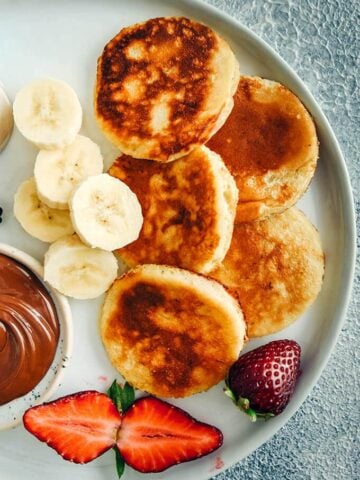 香蕉酸奶煎饼，香蕉片，草莓和巧克力放在一个白色的盘子里