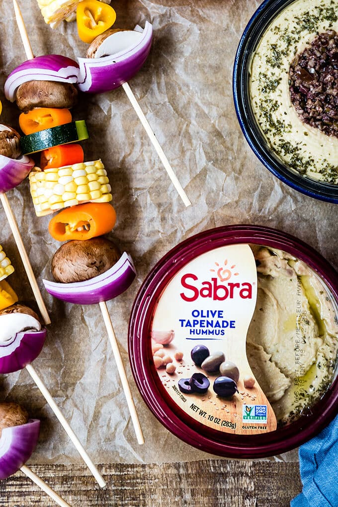 Veggie Kabobs with a simple tangy marinade are so tasty and healthy. So vibrant and packed with flavors, these kabobs make a a great side dish to any meal or a perfect summer appetizer. #vegetarian #kabobs #summerparty #partyfood #meatless #appetizer #ad @sabradips 烤纸上的烤串和鹰嘴豆泥碗