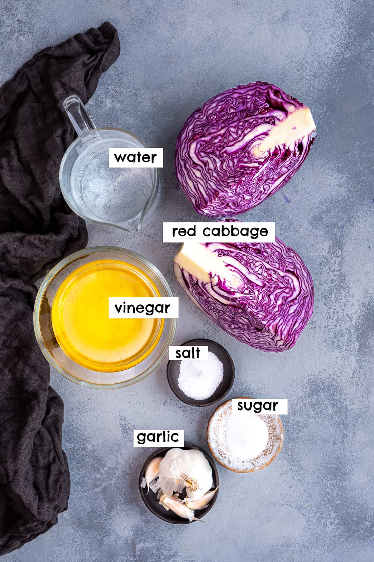 红卷心菜，醋，水，大蒜，盐和糖在浅灰色的背景。