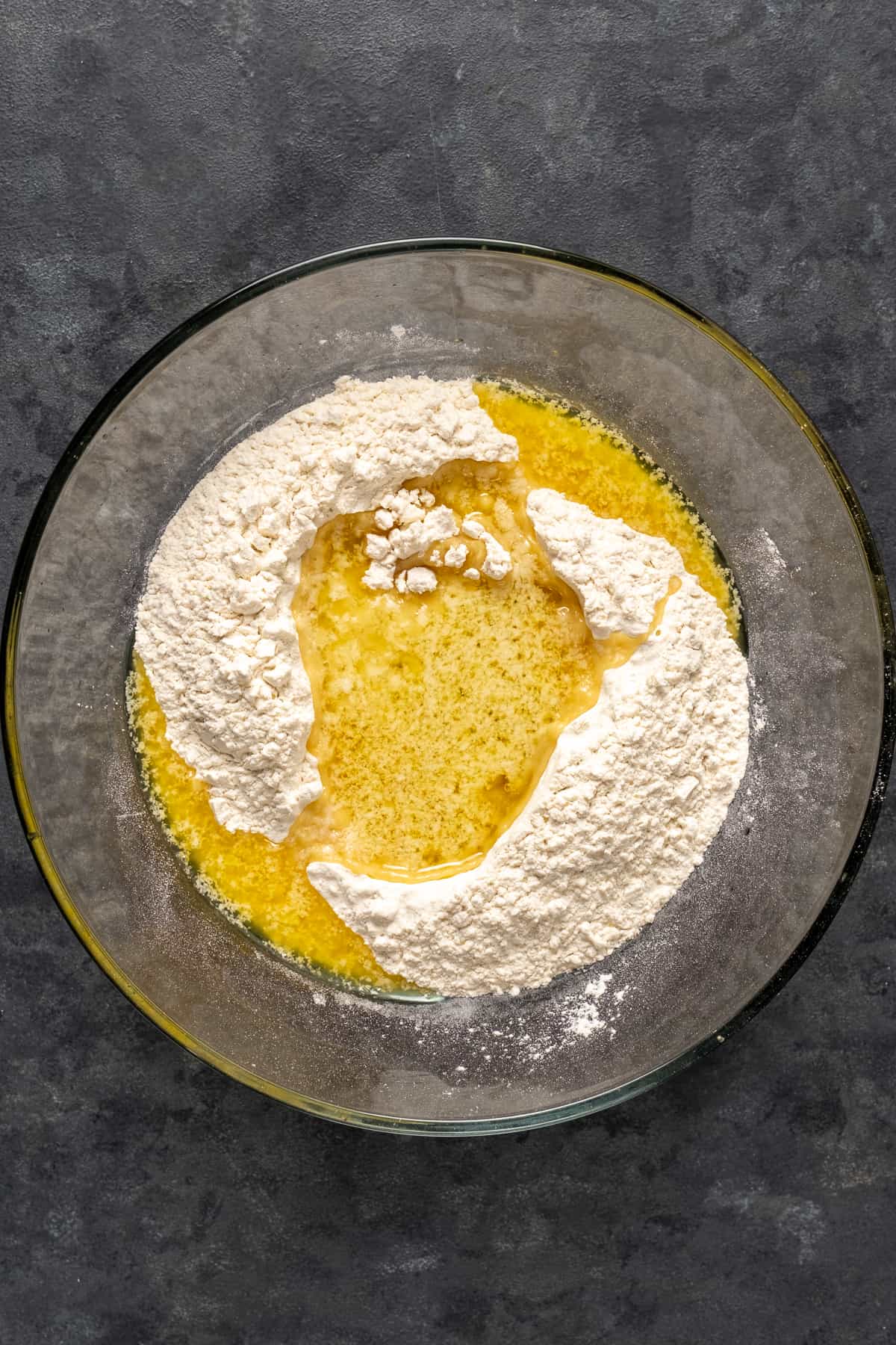 将蛋糕粉和融化的黄油倒入玻璃碗中。