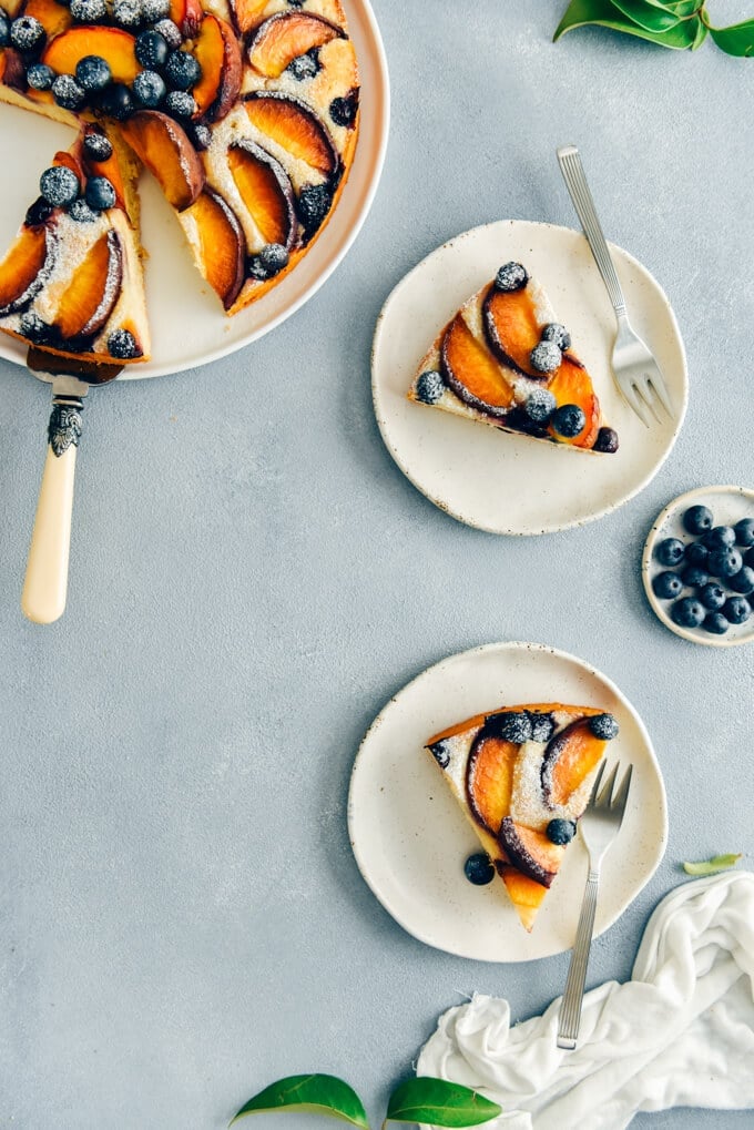This Blueberry Peach Coffee Cake is a luscious cake that is sure to be a crowd pleaser. Made with olive oil and kefir, this simple cake is moist, tender and so light. #peachcake #peachcoffeecake #peachrecipe #coffeecake #kefircake #kefirrecipes 桃子咖啡蛋糕配方与开菲尔照片在白色盘子