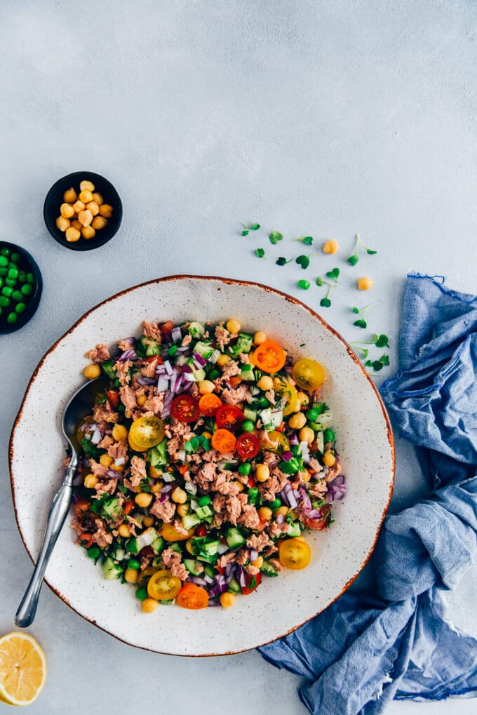 Chickpea Tuna Salad Recipe with a shallot vinaigrette is full of amazing flavors. Packed with protein, fibre and fresh ingredients, this salad is healthy, tasty and keeps you full until dinner time. #tunasalad #chickpeasalad #healthyeating 鹰嘴豆金枪鱼沙拉,配黄瓜、洋葱和西红柿,装在白色的碗里
