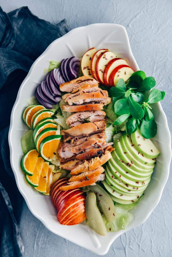 Chicken Salad with Apples is loaded with crisp apples, juicy oranges and red onions. The mouthwatering yogurt dressing with pickles makes this fall salad a big hit. #chickensalad #fallsalad #chickenapplesalad 鸡肉沙拉,苹果,生菜,马齿苋,橙片在一个白色的沙拉碗。