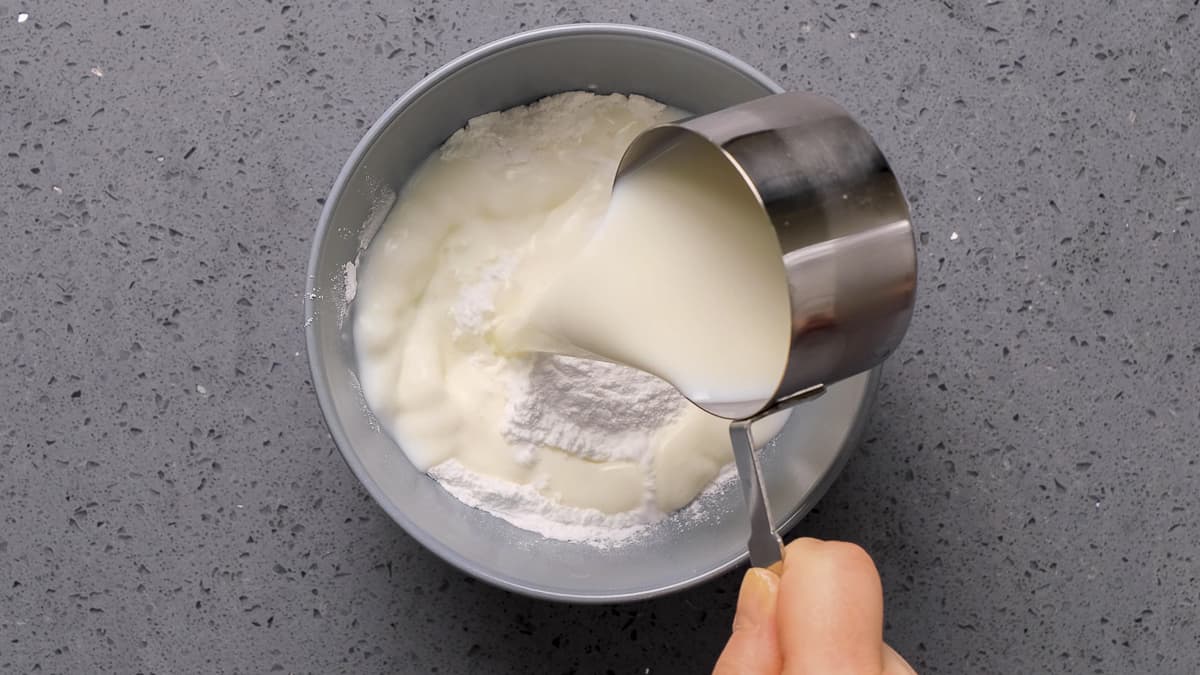 用手把牛奶倒在碗里的玉米上。