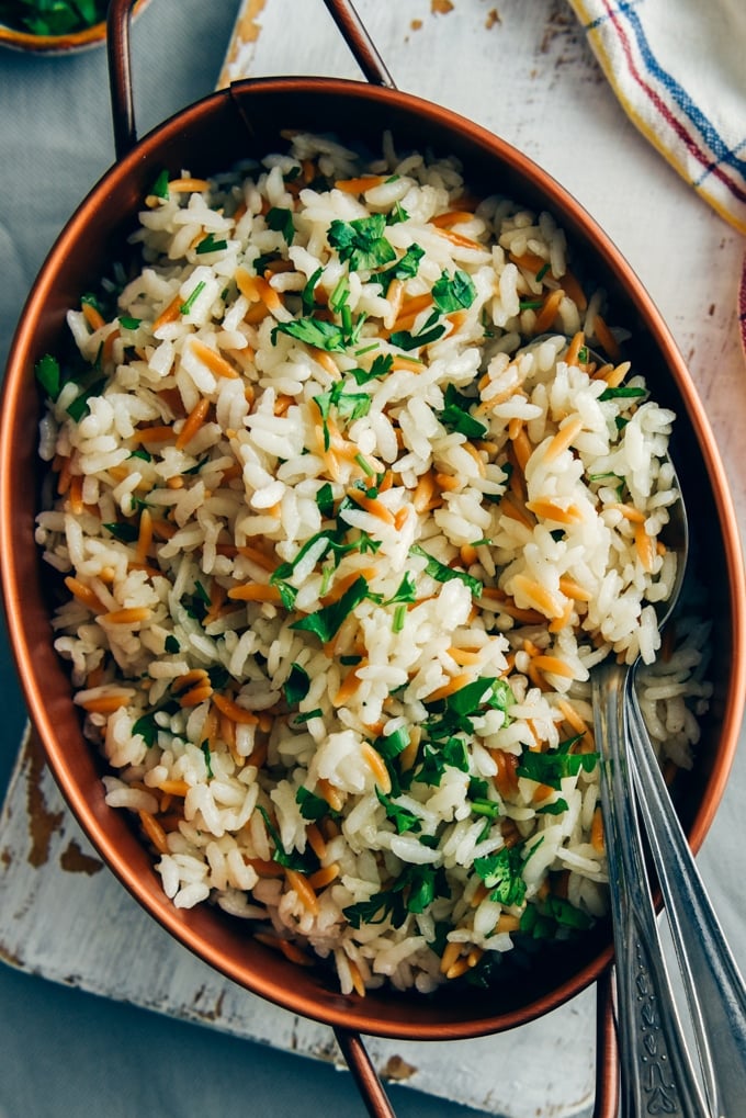 This Rice Pilaf With Orzo is my ultimate side dish that pairs well with anything. Perfectly fluffy every time! #ricerecipe #ricepilaf #sidedish #vegetarianside 米饭饭配意大利面,用铜锅盛着,旁边放着两把勺子。