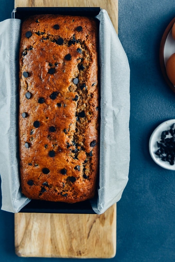 The best Chocolate Chip Banana Bread Recipe. Moist, packed with chocolate chips and tastes like banana. #bananabread #chocolatechipbananabread 巧克力香蕉面包放在烤盘上,放在木砧板上。