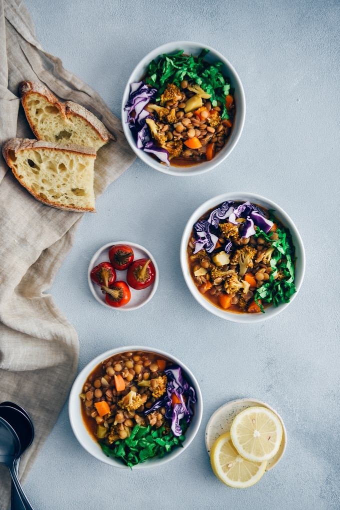 素食小扁豆炖西兰花和胡萝卜，配以红卷心菜丝和欧芹碎，装在白色的碗里。