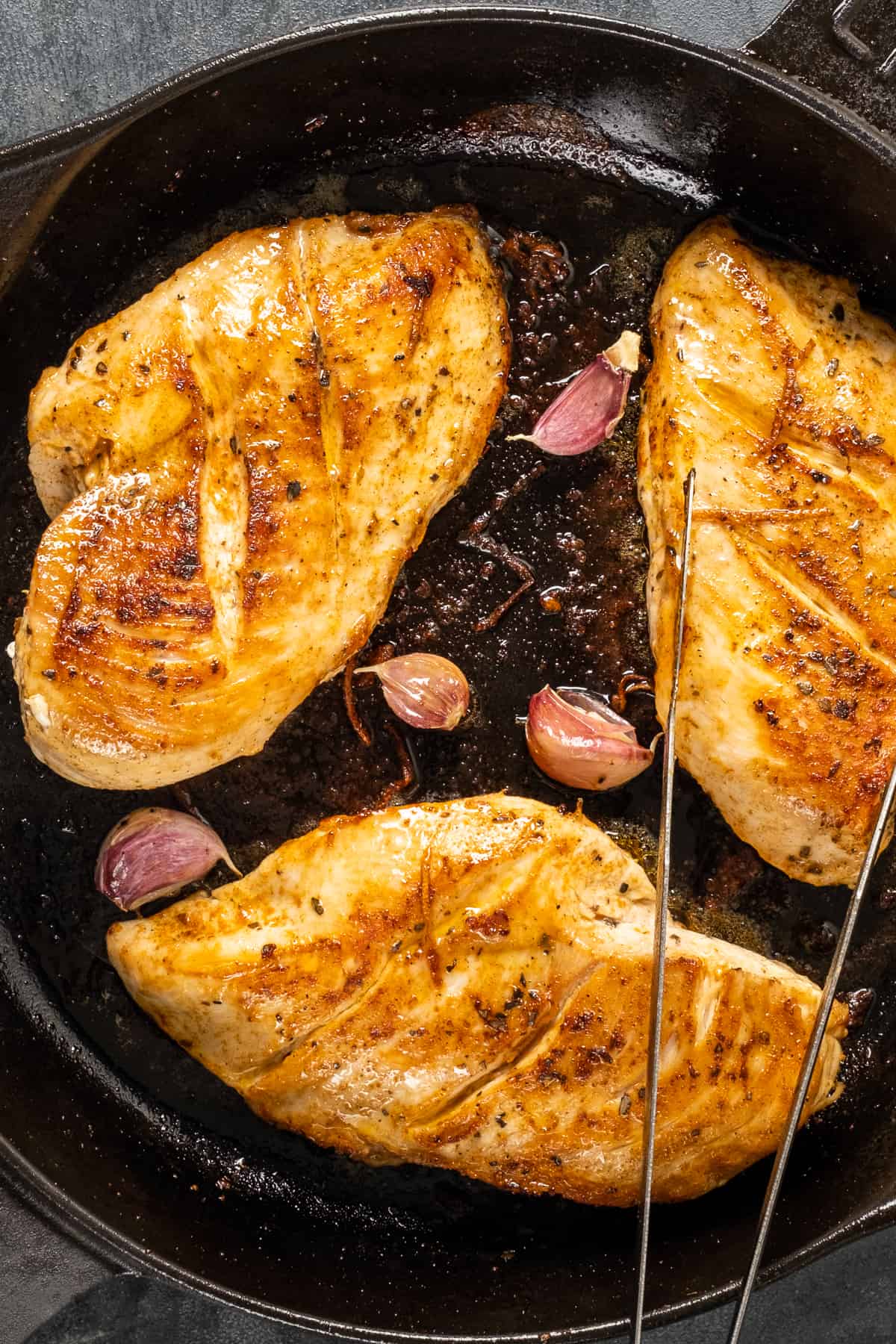 金黄色的鸡胸肉和蒜瓣，连皮放在铸铁锅里。