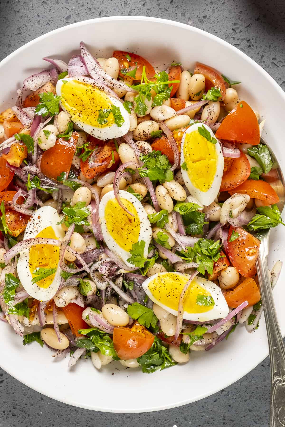 豆子沙拉，西红柿和鸡蛋，放在白色的碗里。
