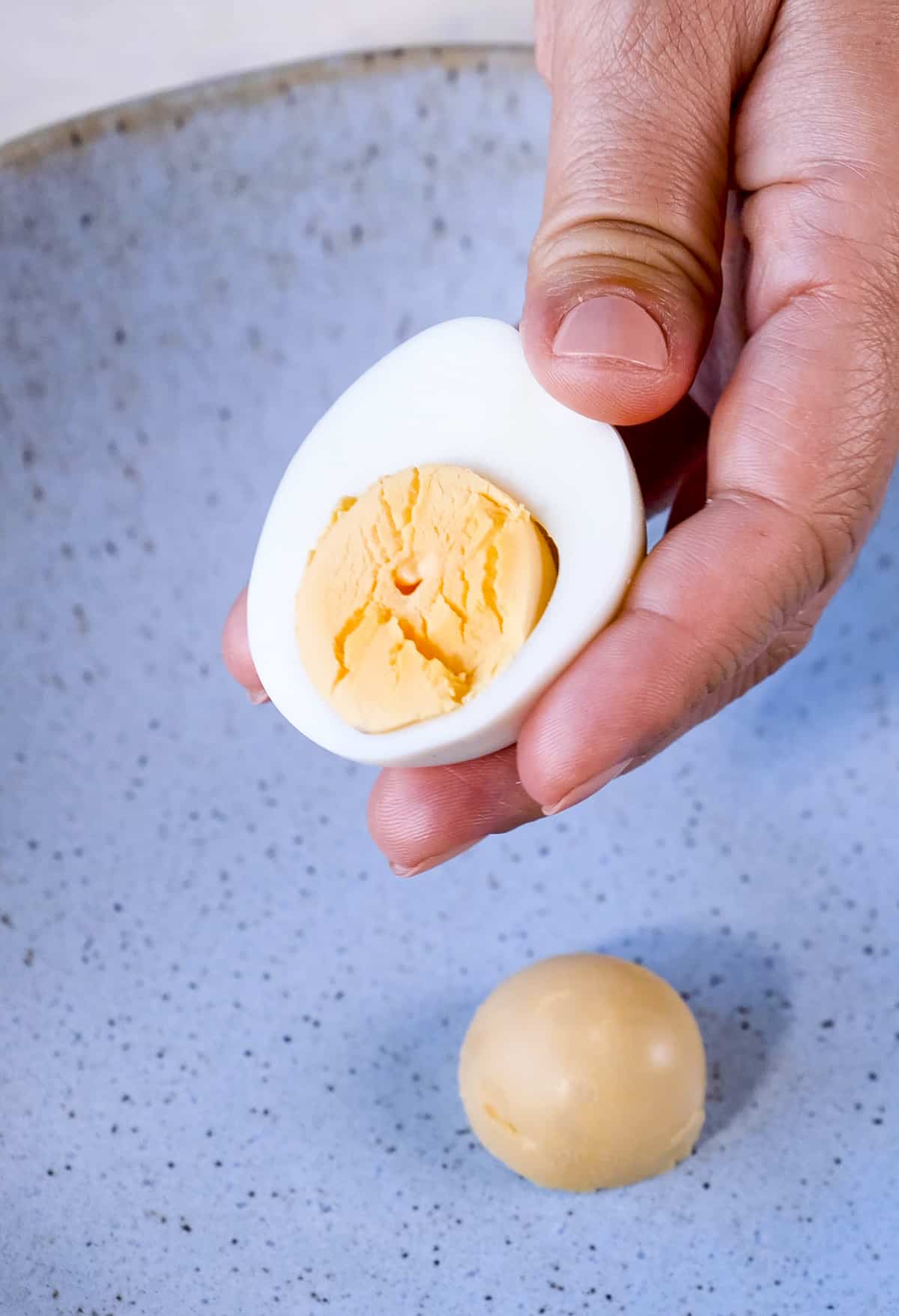 用手轻轻挤压半个煮熟的鸡蛋，使蛋黄变松。