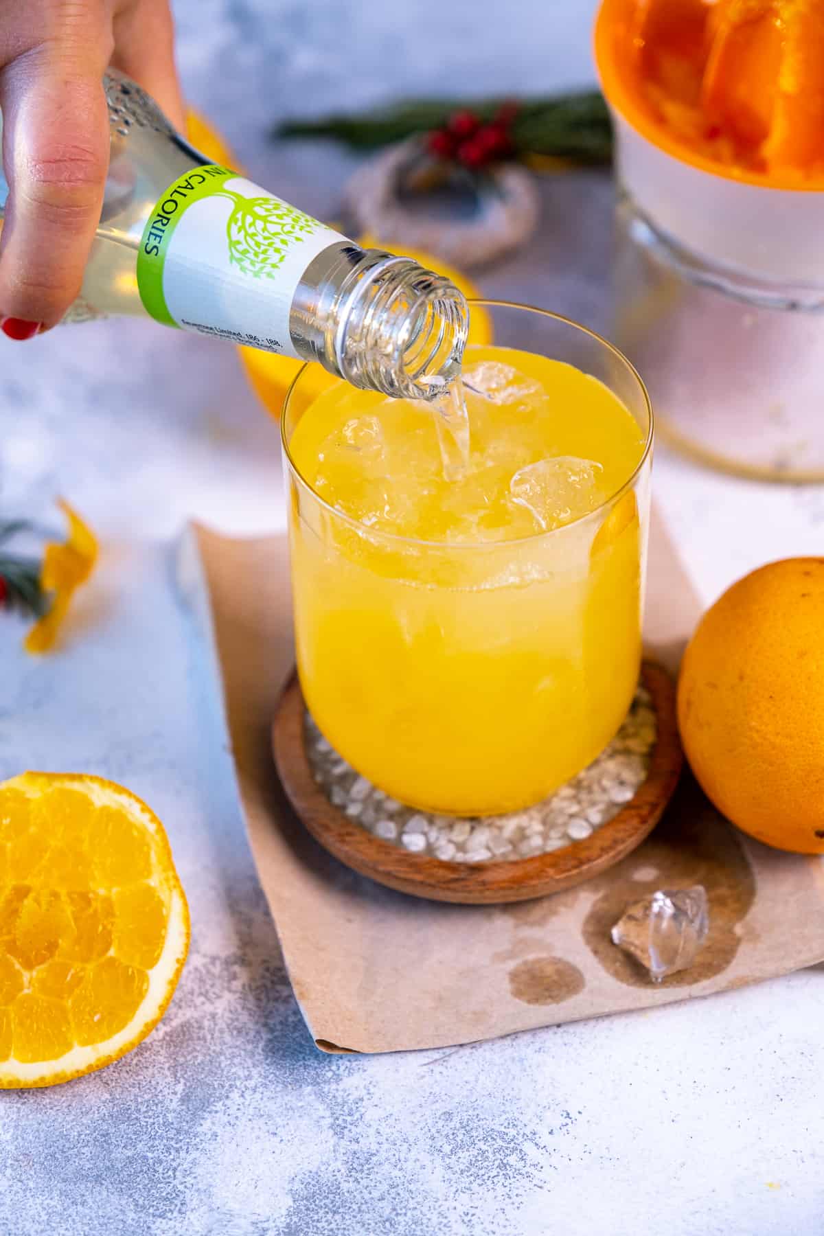 一只手将酸橙苏打倒在伏特加橙鸡尾酒上。
