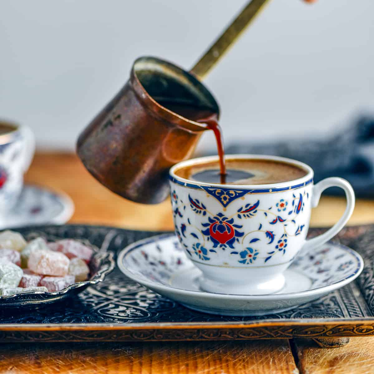 将土耳其咖啡从铜壶倒进传统咖啡杯。