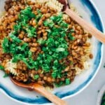 纯素波伦亚的点缀以新鲜parsley in a white bowl with two wooden spoons.