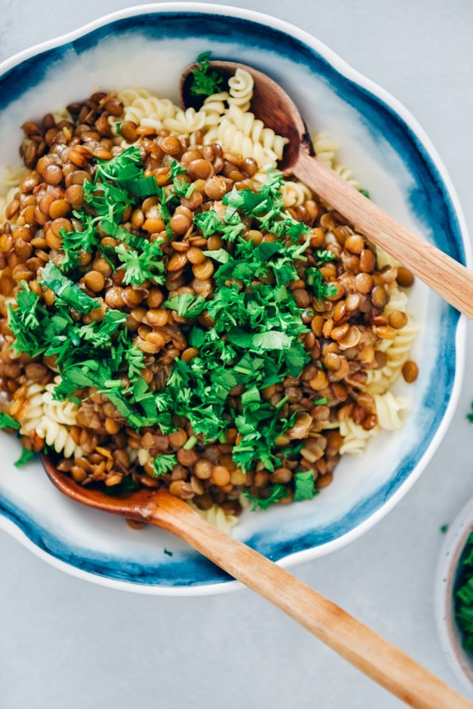 Vegan bolognese using lentils is a wonderful alternative to classic bolognese sauce. This is the most innocent AND TASTIEST pasta sauce ever! #veganrecipe #veganbolognese #lentilbolognese #lentilrecipes 用新鲜欧芹装饰的素食肉酱,放在一个白色的碗里,用两个木勺。
