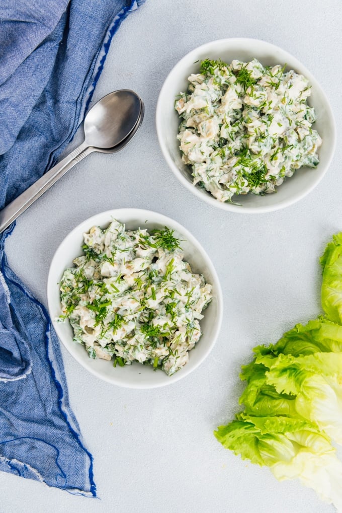 Low carb chicken salad recipe with herbs and walnuts makes a satisfying lunch with lettuce leaves. So easy to make! #chickensalad #lowcarbsalad #lowcarbchickensalad 低碳水化合物鸡肉沙拉食谱,希腊酸奶,蛋黄酱,核桃,香草和芥末在两个白色的碗。