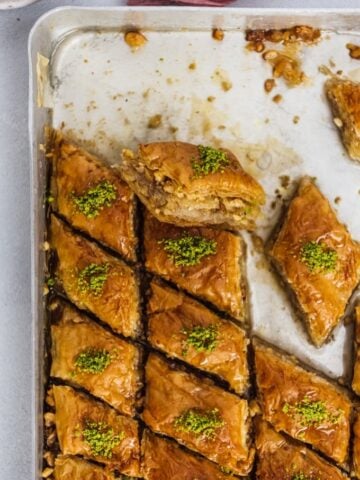 Newly baked Turkish baklava dessert filled with walnuts and topped with pistachio in a baking sheet