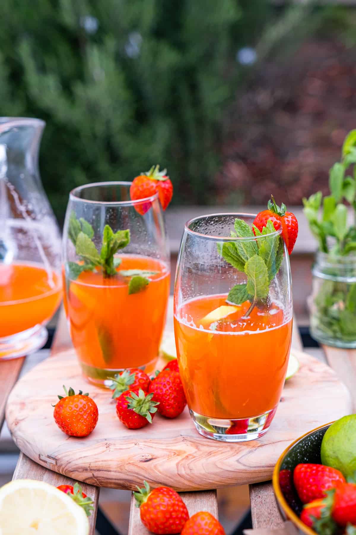 草莓柠檬水装在高脚杯里，用薄荷叶、草莓和柠檬叶装饰。