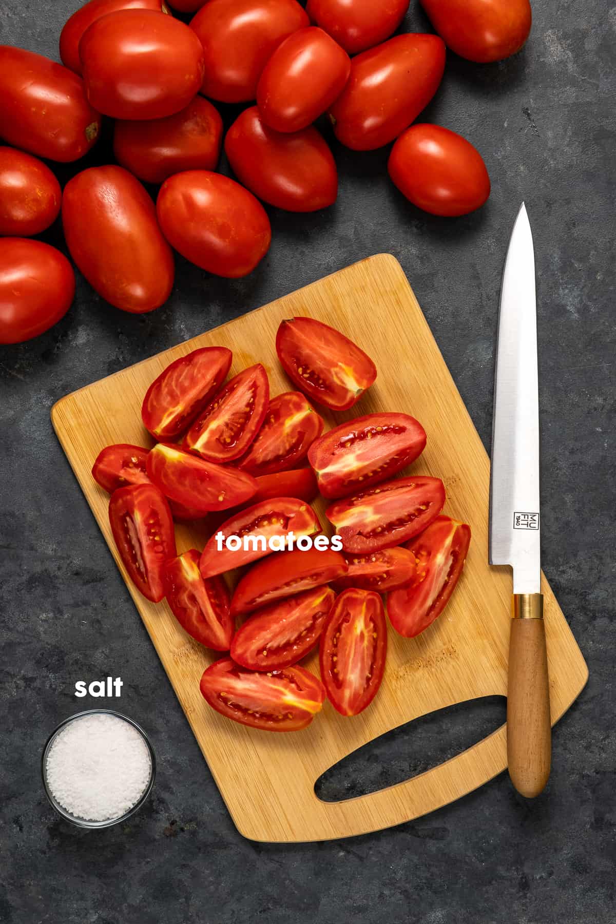 切菜板上放上切好的西红柿，切菜板上放上一把刀，小碗里放上粗盐，旁边放上整个西红柿。