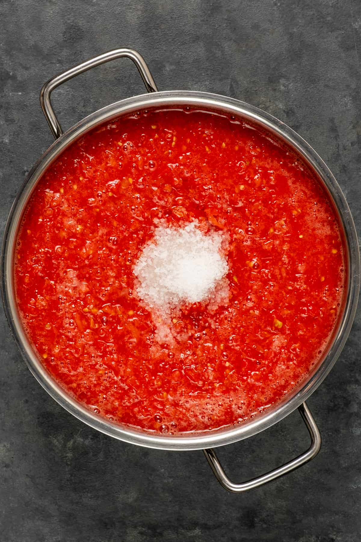 将番茄泥放入深锅中，在上面撒一些粗盐。