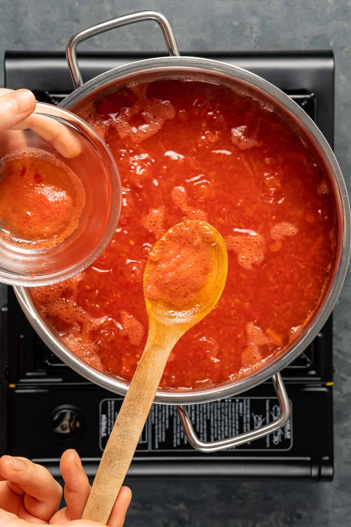 用木勺将锅里煨着的番茄酱上的泡沫去除。