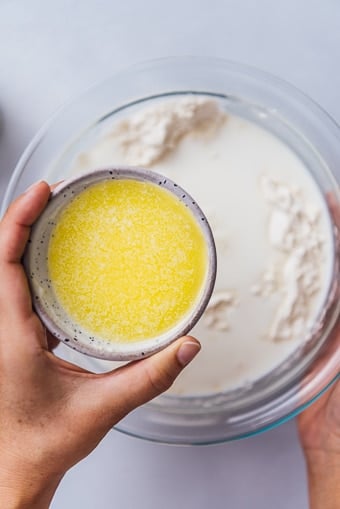 用手将融化的黄油倒入玻璃碗中。