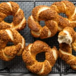 金黄色脆脆的土耳其甜饼，上面裹着烤芝麻，放在黑色的冷却架上，背景是黑色的。