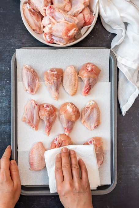 手pat烘干鸡翼在烘烤板材使用纸毛巾。
