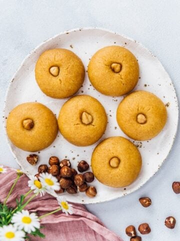 用糖浆浸泡过的小麦粉饼干放在陶瓷盘子里，配上榛子和春花