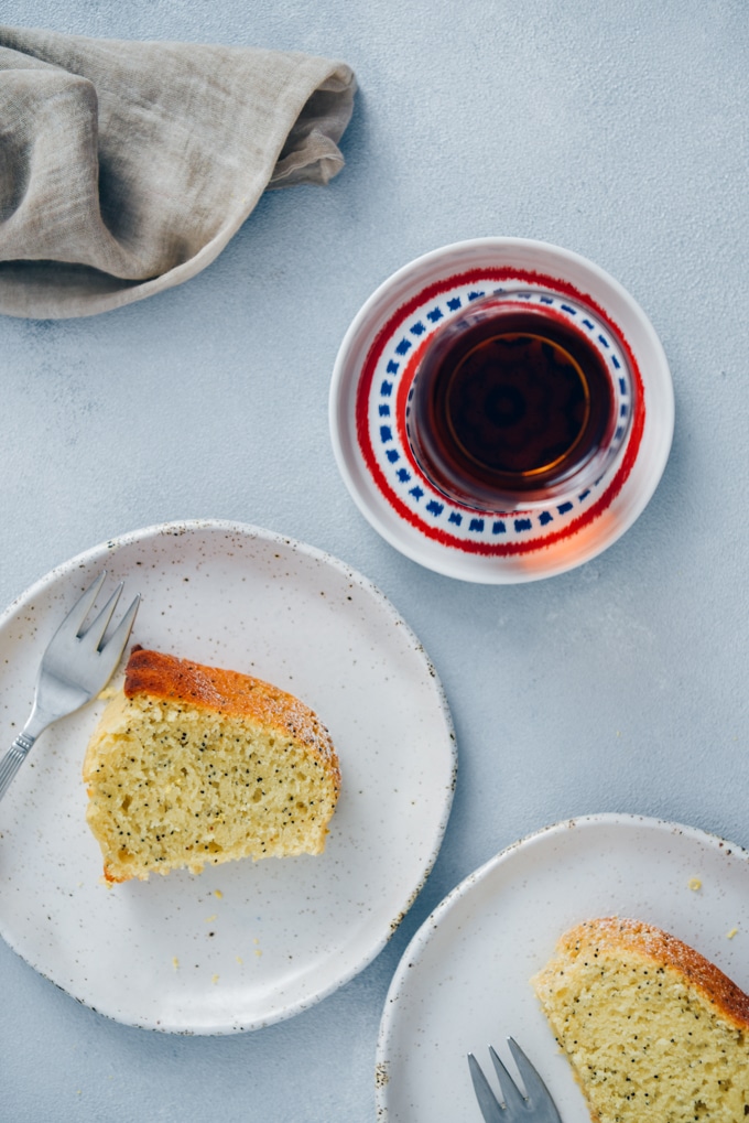 切片柠檬罂粟种子蛋糕在白色陶瓷板供应陪同着一杯土耳其茶。