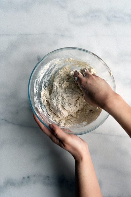 用手在玻璃搅拌碗中搅拌无酵母的面包面团成分。