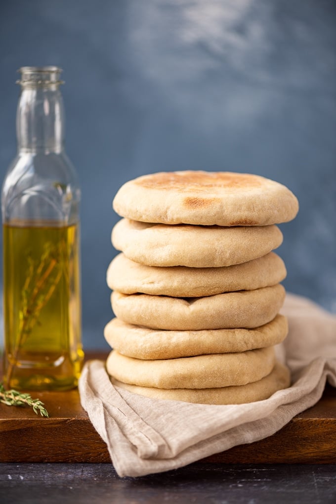 一堆被称为bazlama的土耳其大饼放在木板上，一瓶橄榄油和新鲜的百里香伴着。