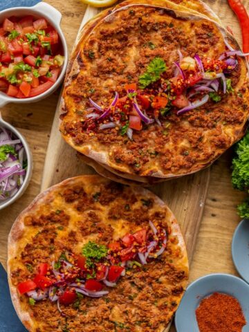 自创土耳其拉马村服务用红洋葱沙拉和蕃茄沙拉作为在一个木板的调味品。香料，柠檬切片，一堆欧芹和辣椒陪伴。