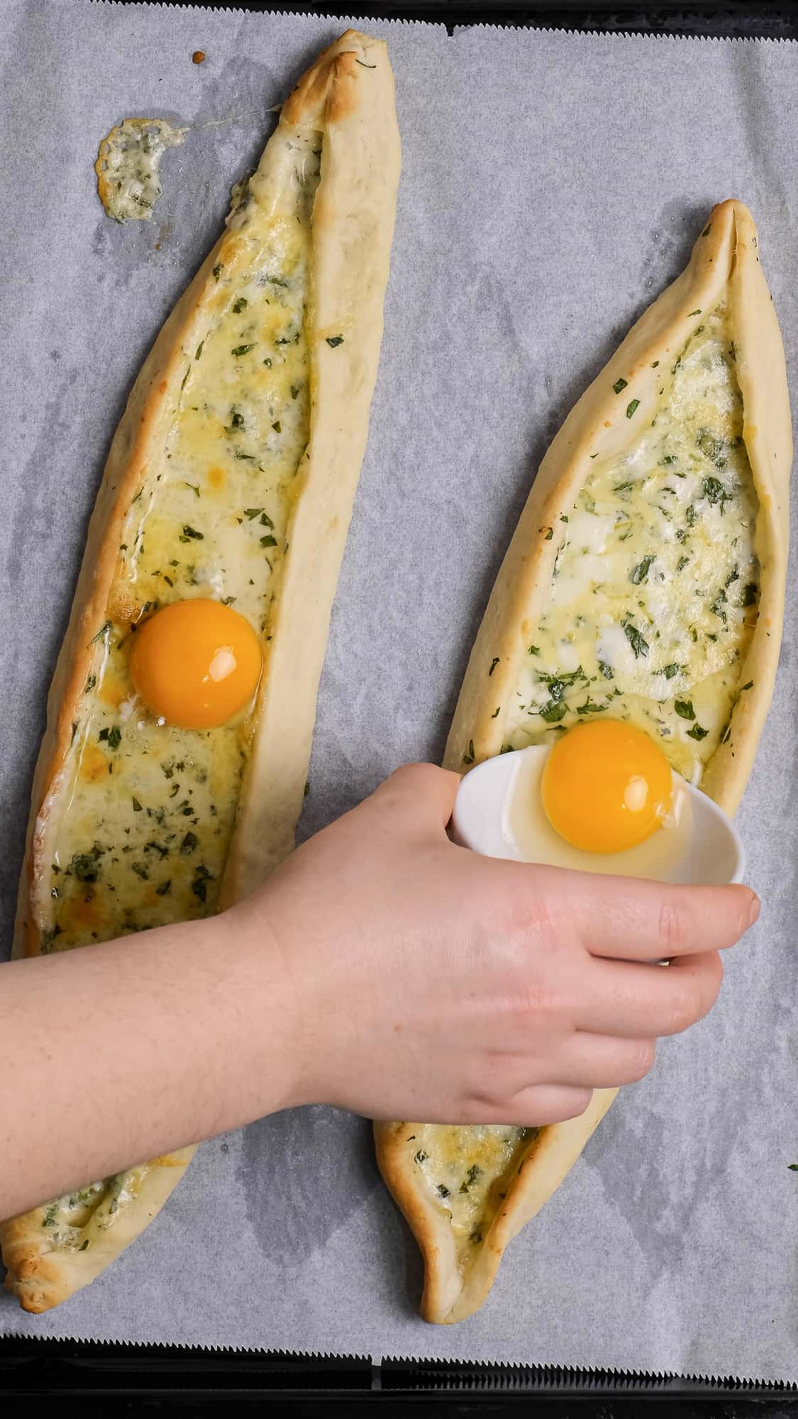 一只手把鸡蛋放在两块半熟的奶酪上。