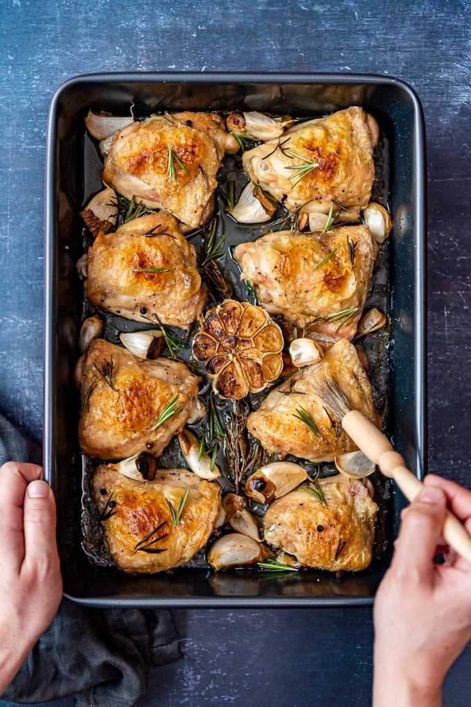 Brushing chicken thighs with the juice in the baking pan