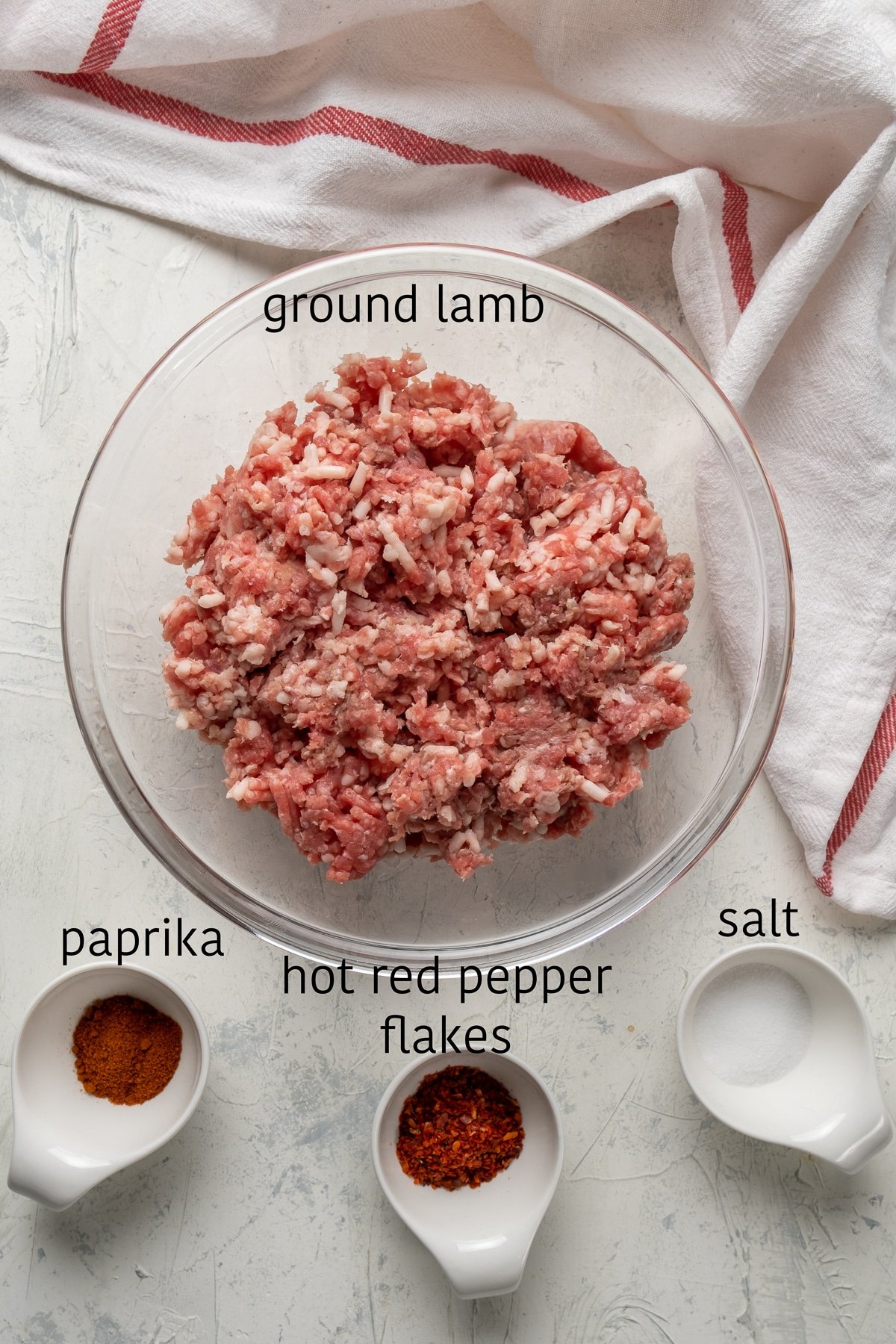碎羊肉放在玻璃碗里，辣椒粉、红辣椒片和盐分别放在旁边的碗里。