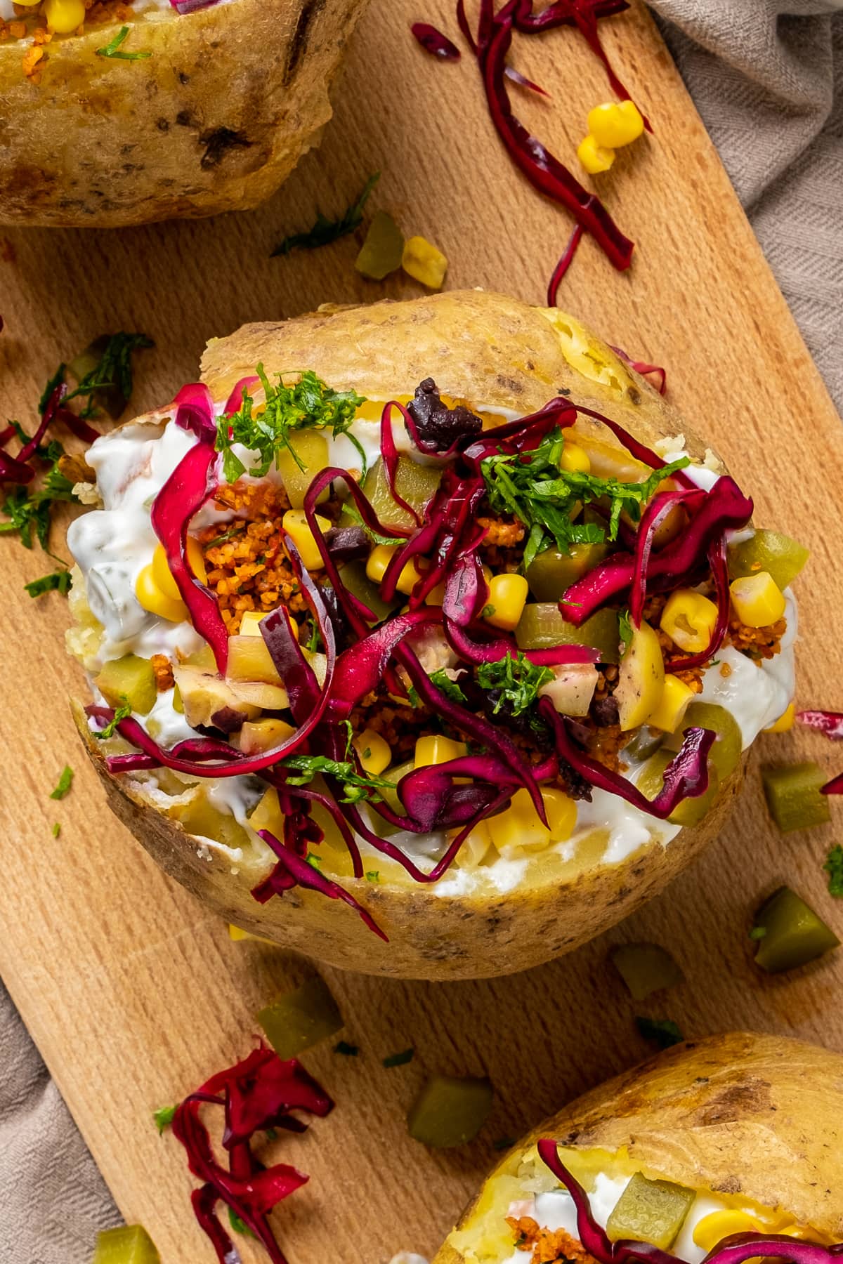 Kumpir装着磨碎的沙拉kisir，玉米，橄榄，莳萝泡菜和红卷心菜放在木板上。