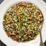 黑眼豌豆沙拉，蔬菜和香草放在一个白色的碗里，勺子在里面。