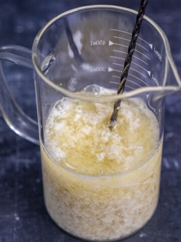杏仁奶和醋混合在一个玻璃量杯和搅拌勺里面。