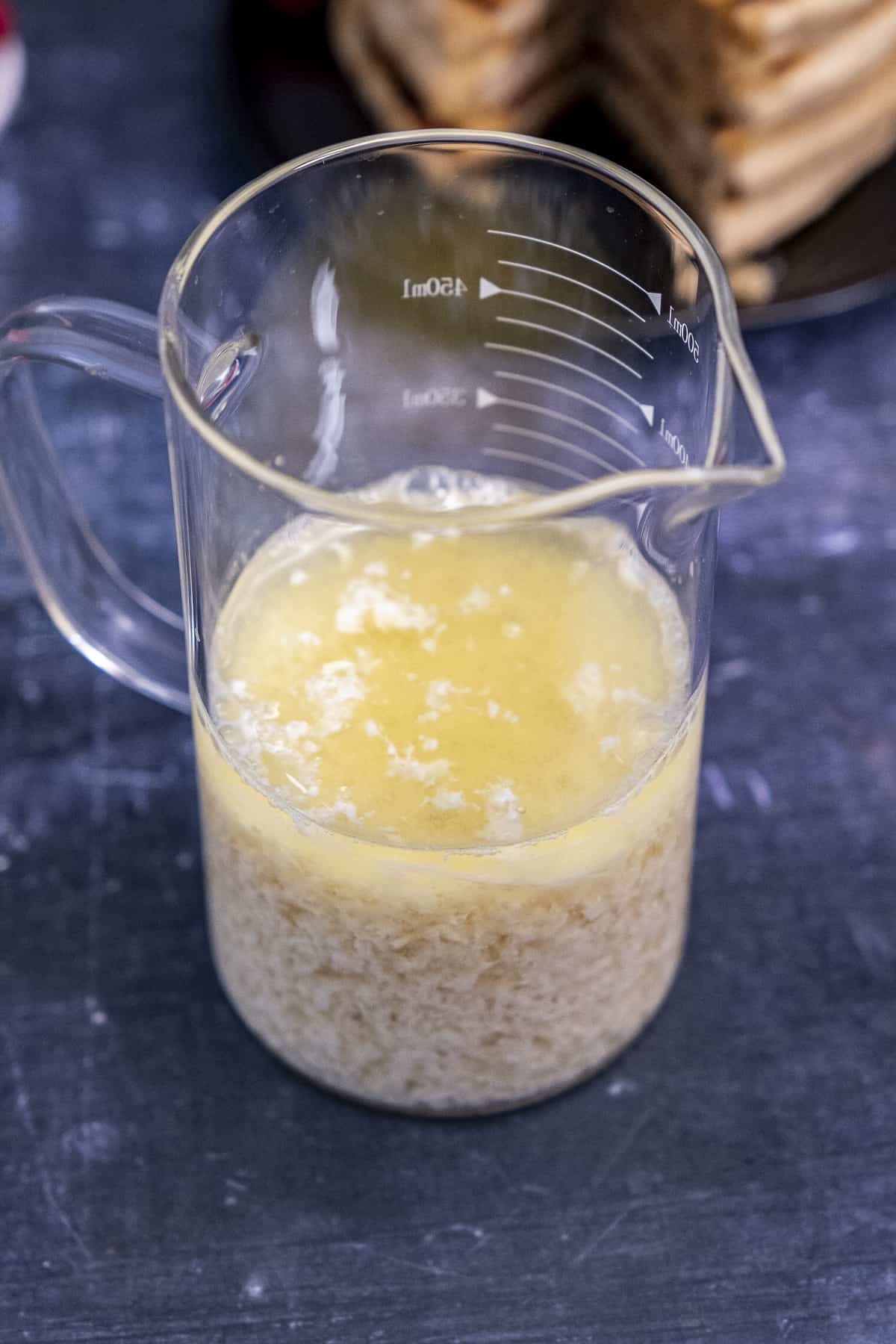 不含乳制品的脱脂牛奶放在玻璃杯里,后面是深色背景的煎饼。
