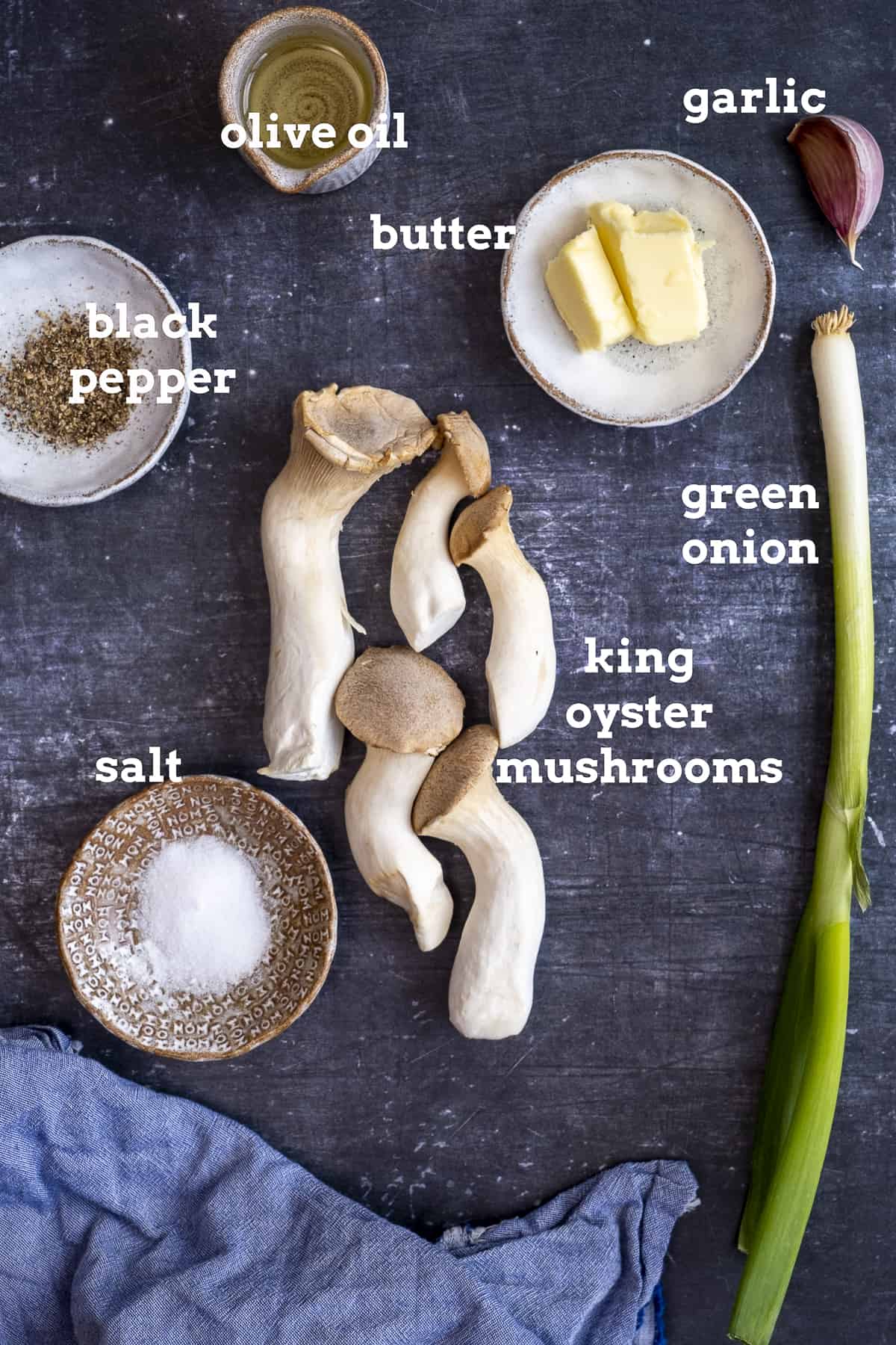 王蚝菇，黄油，油，大蒜，葱花，盐和胡椒，黑色背景。