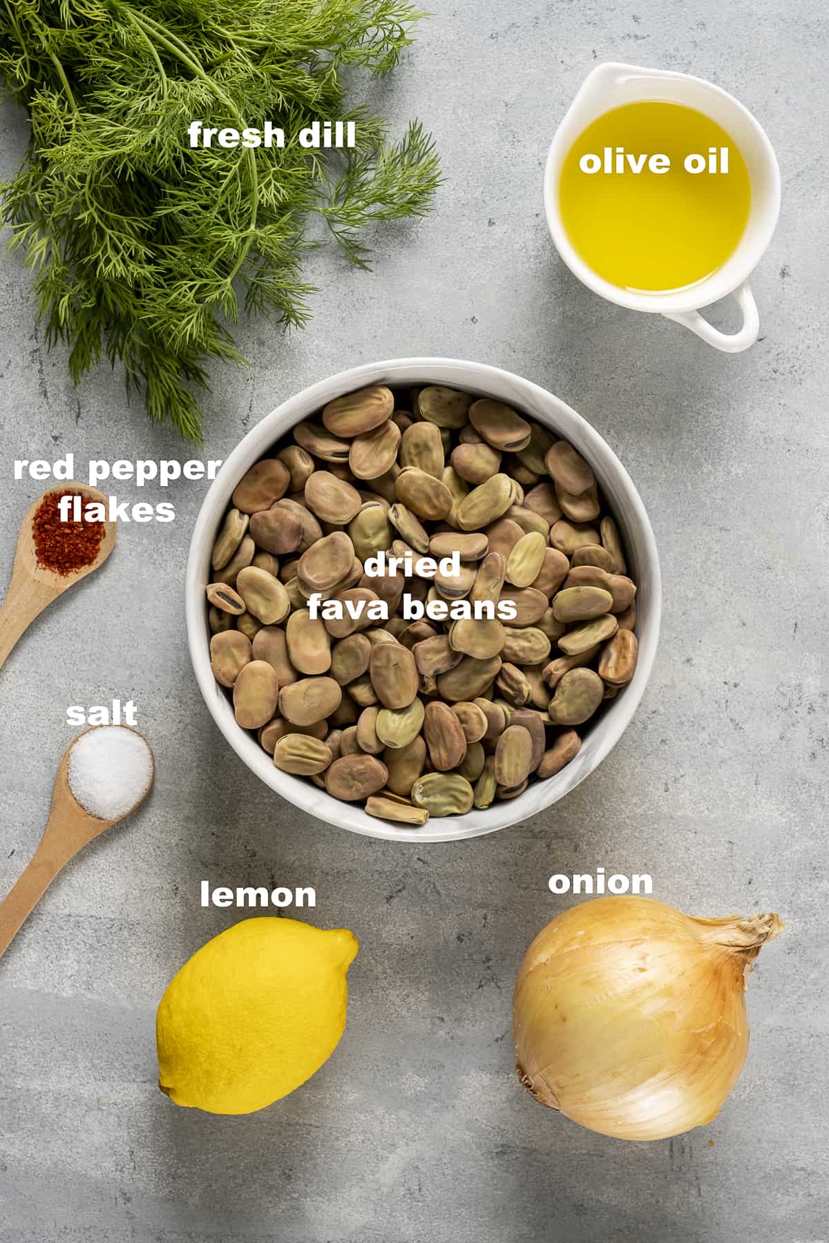 干蚕豆，橄榄油，洋葱，柠檬，新鲜的莳萝，盐和红辣椒片在灰色的背景上。